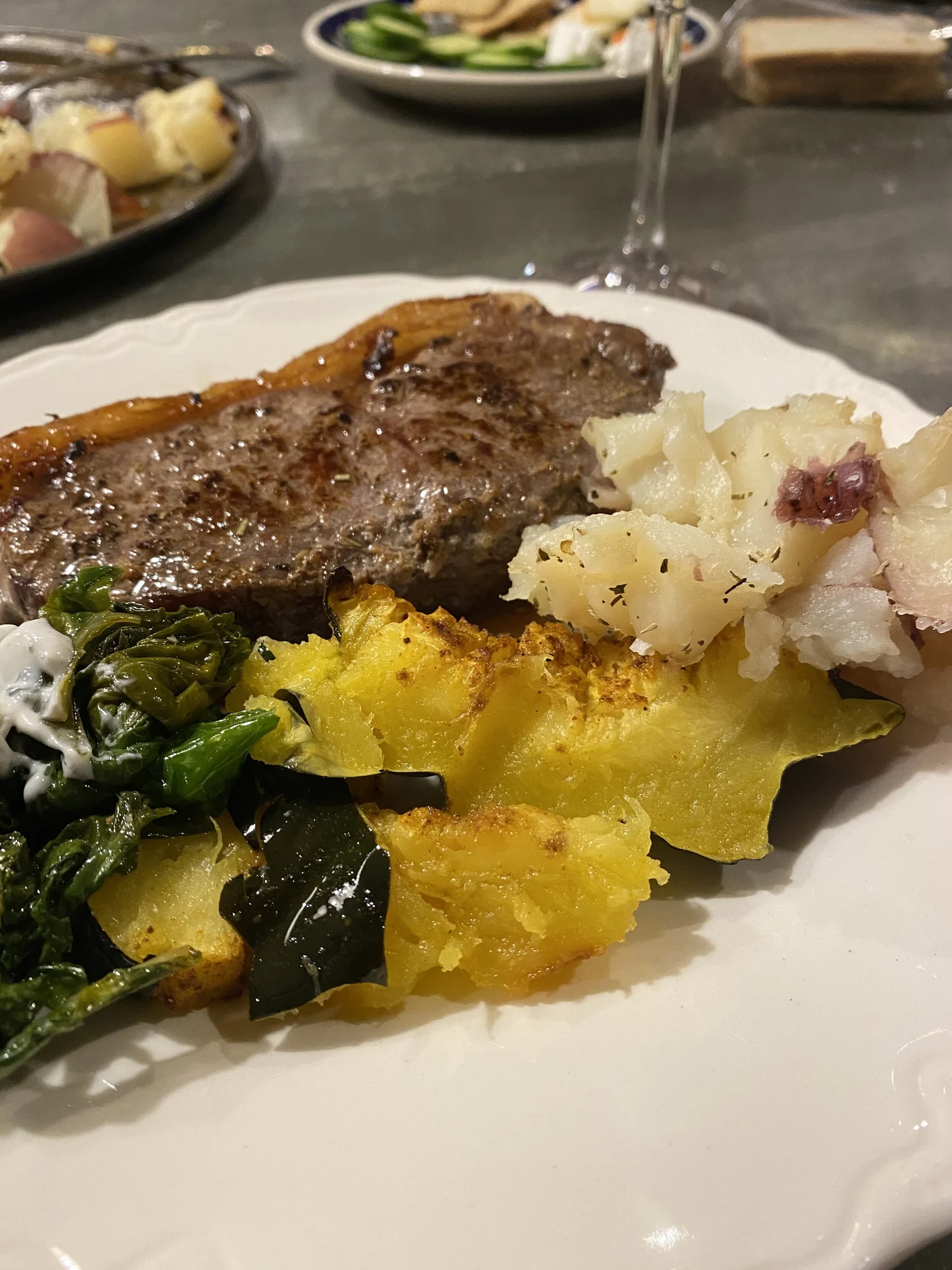 A steak dinner plated with potatoes and greens